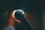A close-up of a microphone with a dark, blurred background, suggesting a stage or performance setting at Design 710 Atlantic City dispensary.