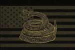 A coiled rattlesnake with its mouth open is depicted in gold lines over a dark, stylized American flag background with muted stripes and stars.