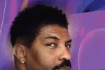 A man with short, curly black hair, a mustache, and an earring looks over his shoulder against a purple and blue abstract background.